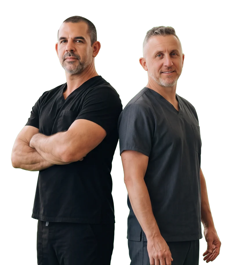 Colin Rigney, arms folded, standing back to back with Ryan Martin, both in dark scrubs